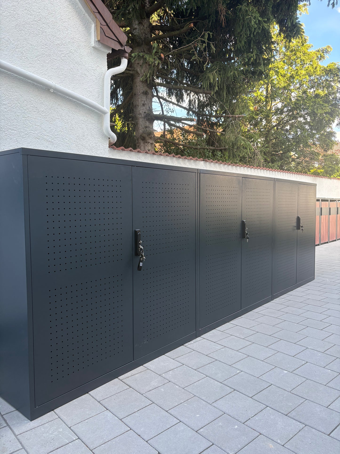 Erfolgreiches Aufbau-Projekt einer mehrteiligen Metall-Fahrradgarage Wallstreet in Anthrazit auf gepflastertem Untergrund im Außenbereich.